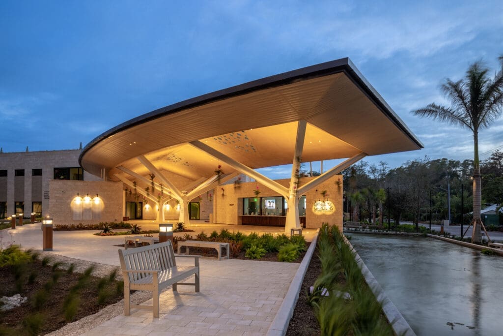 Exterior photo of the front entrance of the Marie Selby Botanical Gardens in the evening with the building lights on.