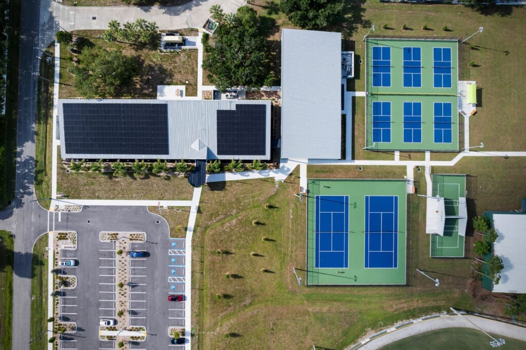 Aerial view of the Sarasota County Parks Administration Building showing rooftop solar panels, the Multi-Purpose Building, tennis and pickleball courts, and parking at Twin Lakes Park.